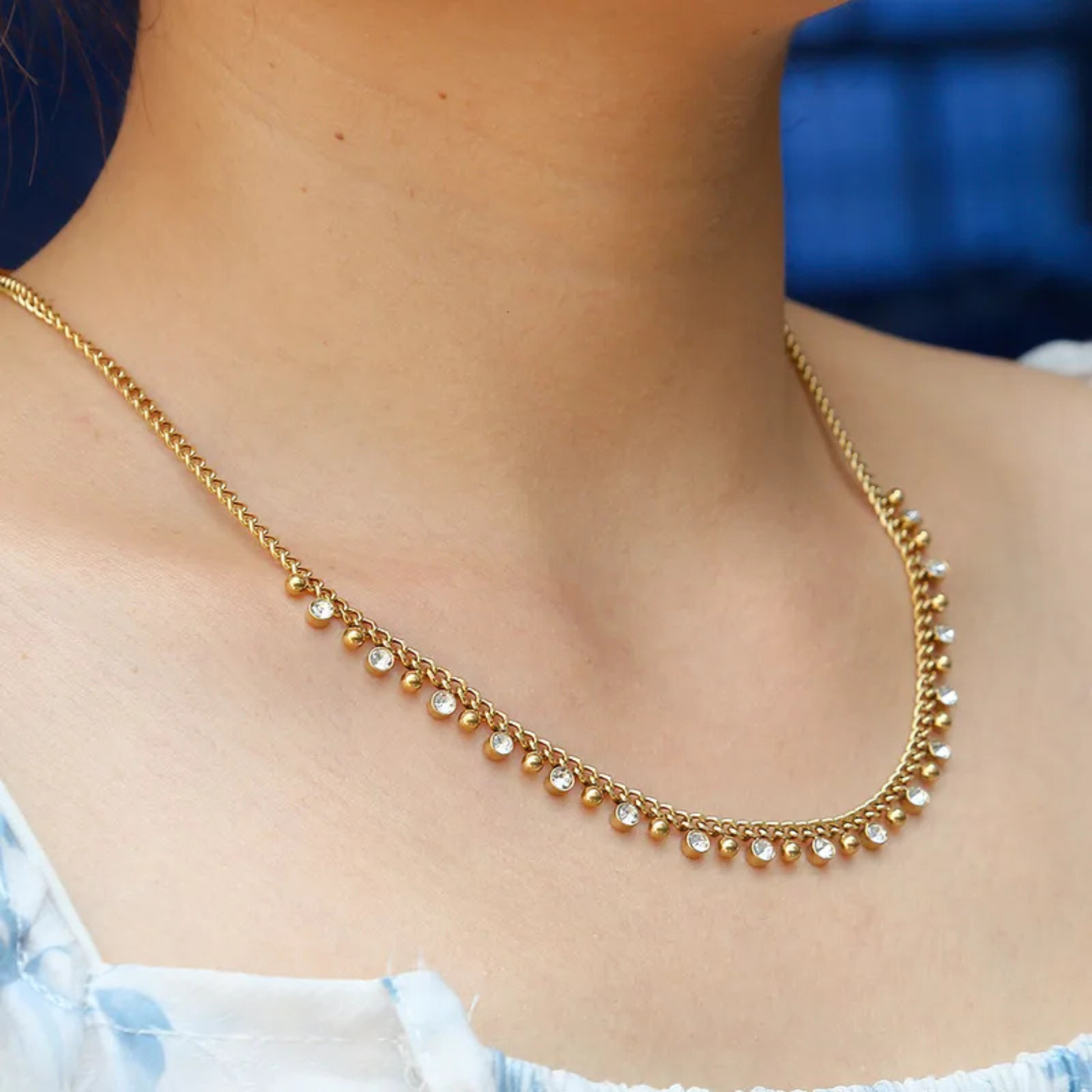 Gold chain necklace on a person's neck with a blurred background