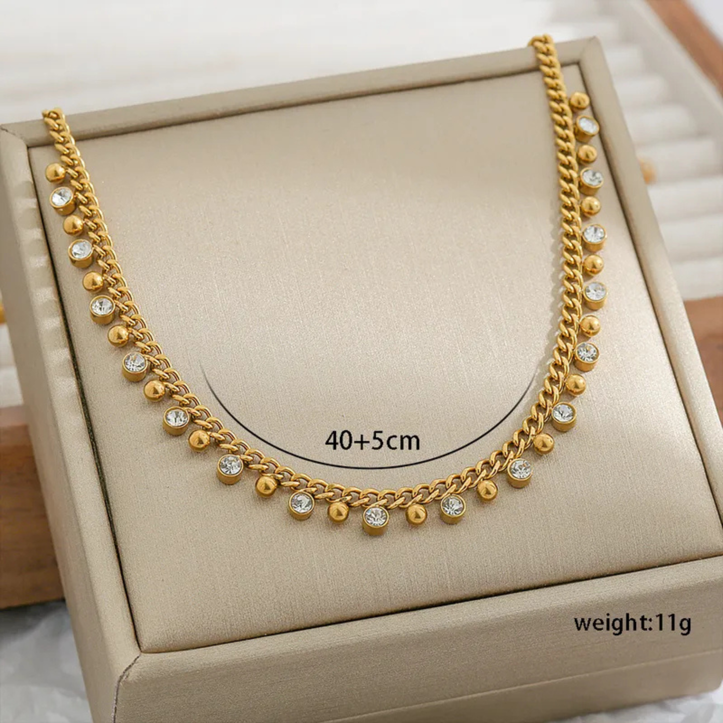 Gold necklace with small diamonds on a beige jewelry box