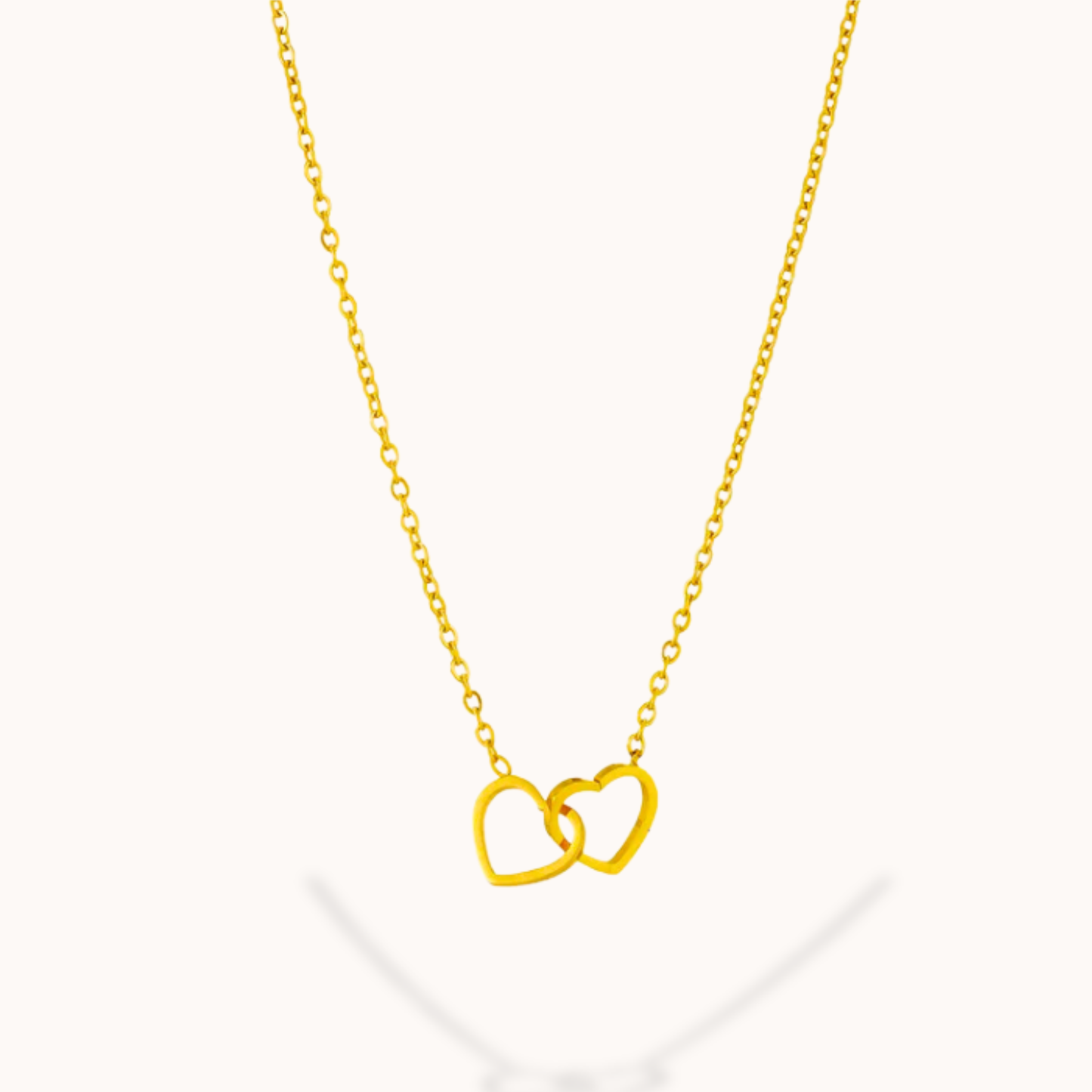 Gold necklace with interlocking heart pendants on a white background