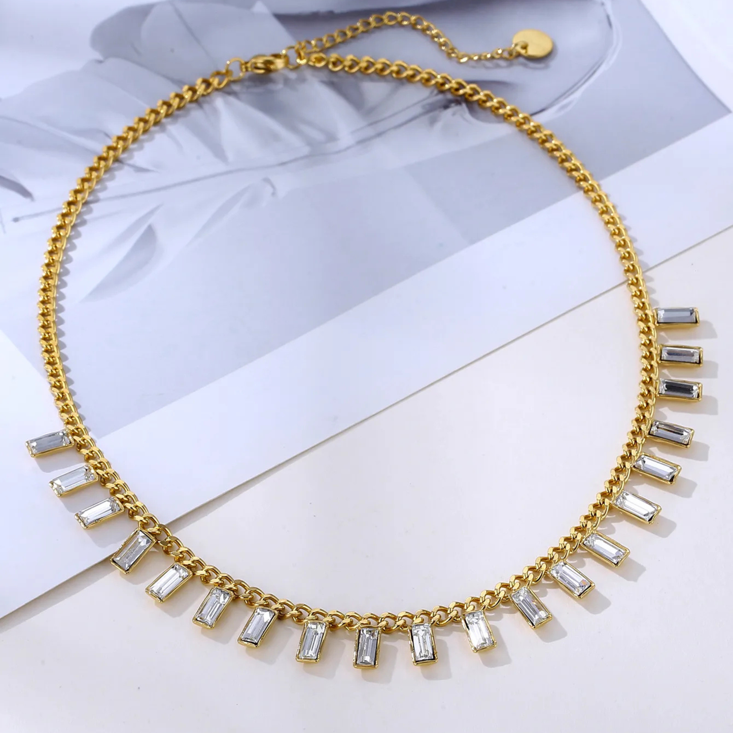 Gold necklace with clear stones on a light background