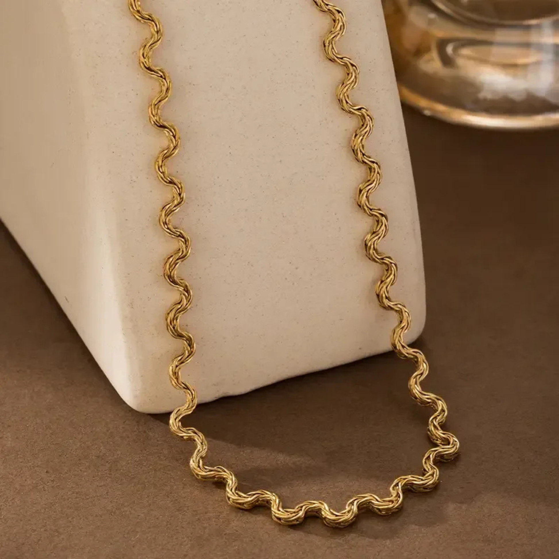 Gold necklace on a textured surface with a neutral background