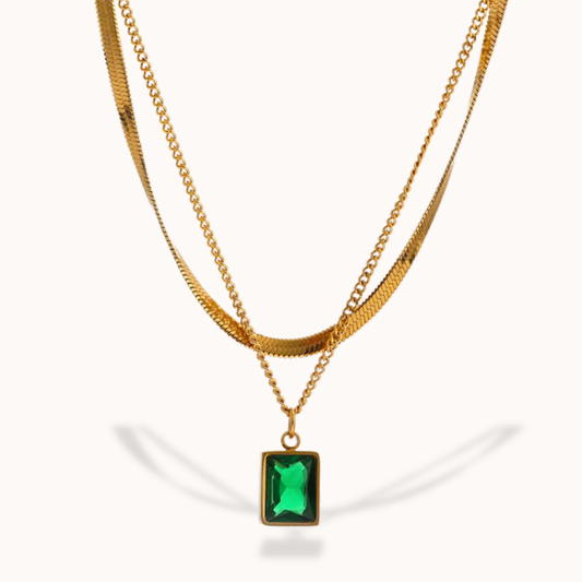 Gold necklace with a green gemstone pendant on a white background