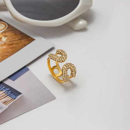 Gold ring with zircons on a light surface with a magazine and cup in the background