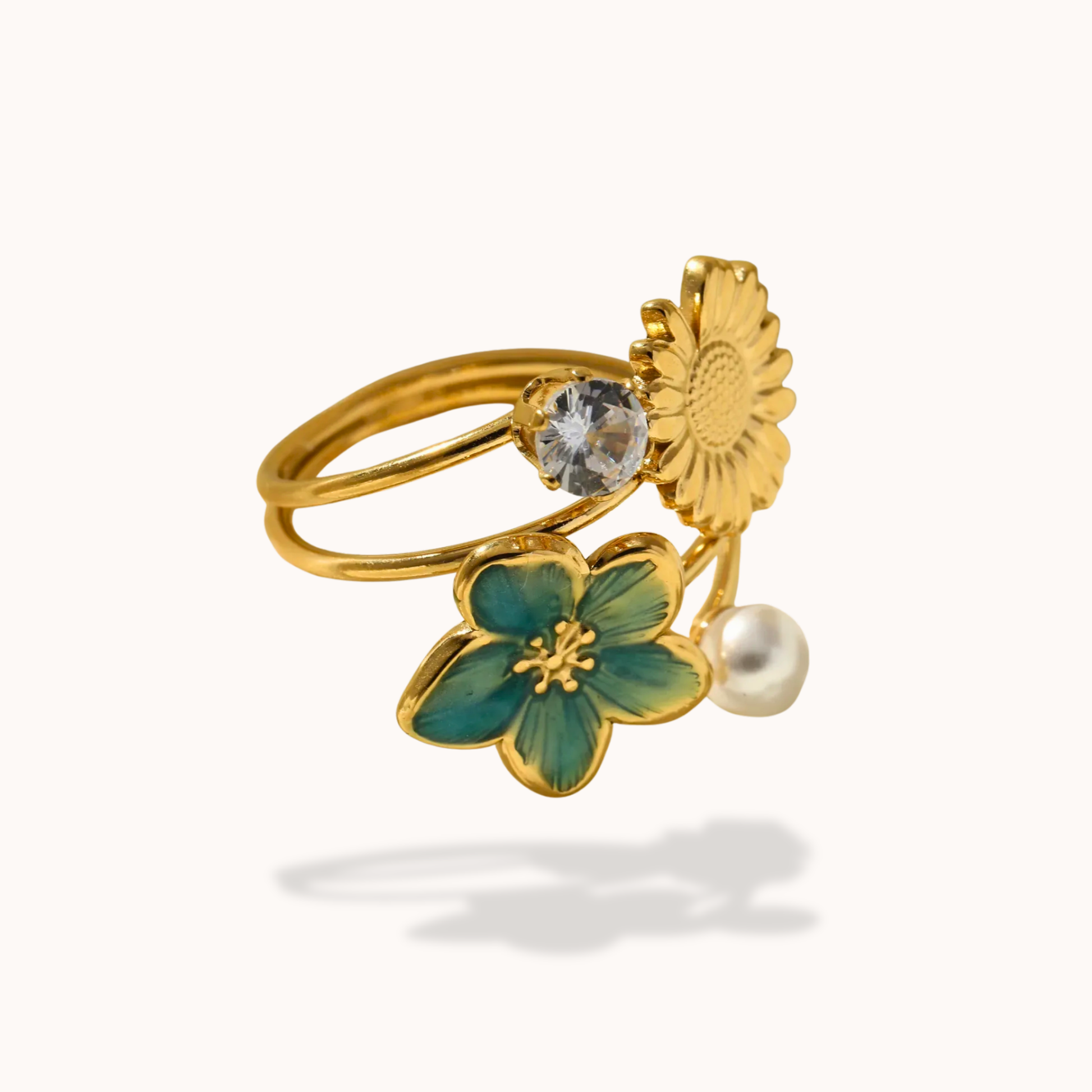 Gold ring with green flower, clear gem, and pearl on a white background