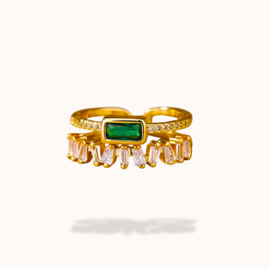 Gold ring with green gemstone and clear stones on a white background