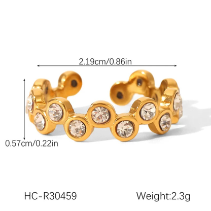 Gold-colored ring with embedded crystals and measurements on a white background