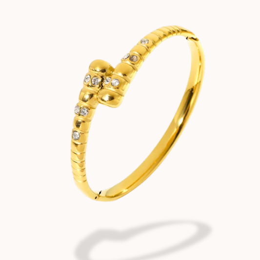 Gold bangle with small diamonds on a white background