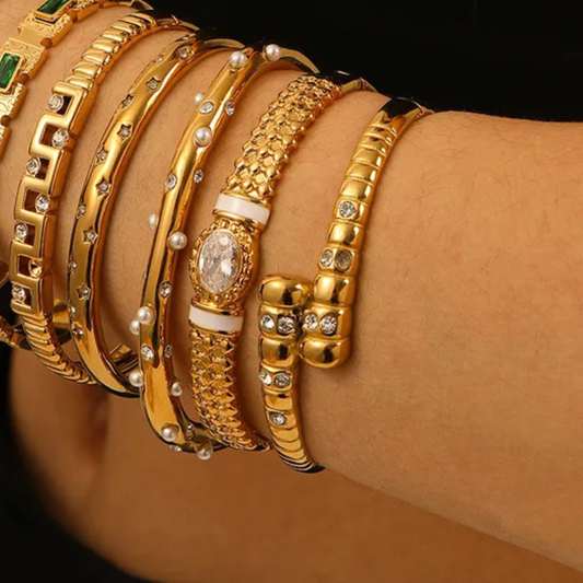Close-up of a wrist wearing multiple gold bracelets with various designs.