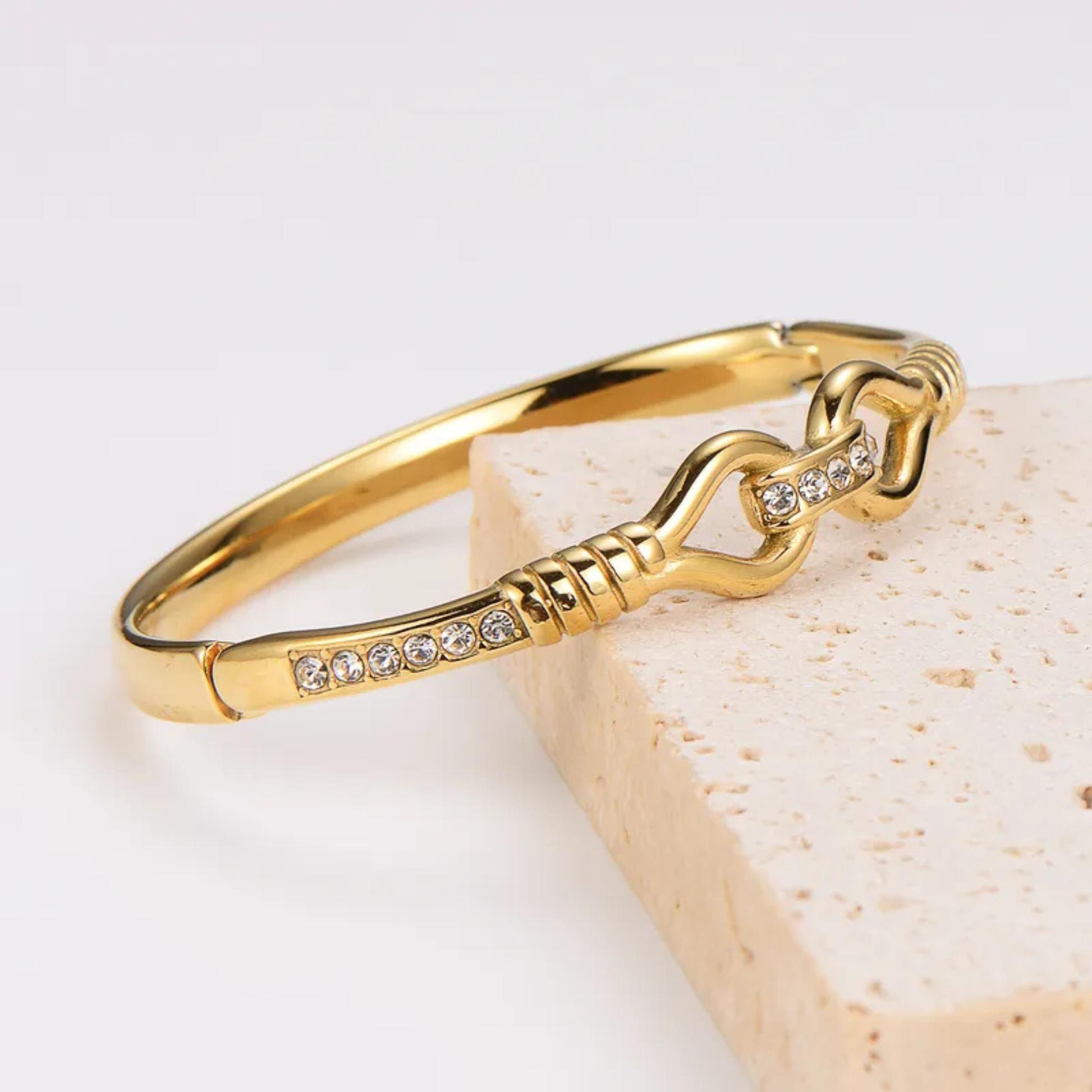 Gold bracelet with chain design and embedded crystals on a light background