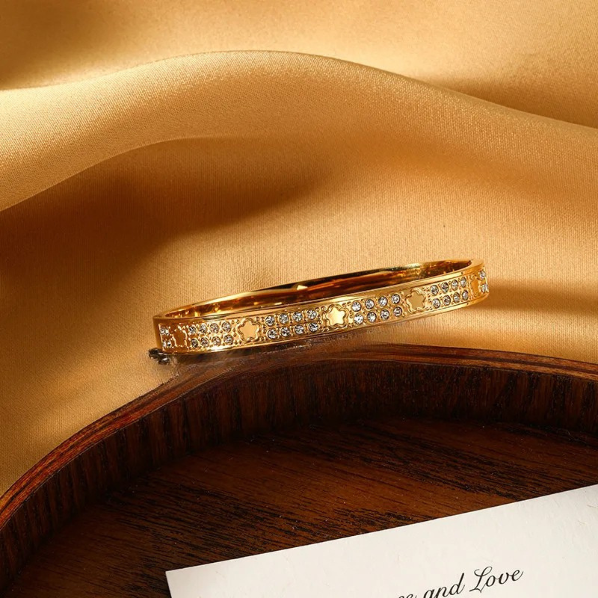 Gold bracelet with gemstones on a beige fabric background