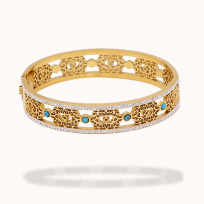 Gold bracelet with intricate design and turquoise stones on a white background