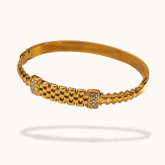 Gold bracelet with a textured design on a white background