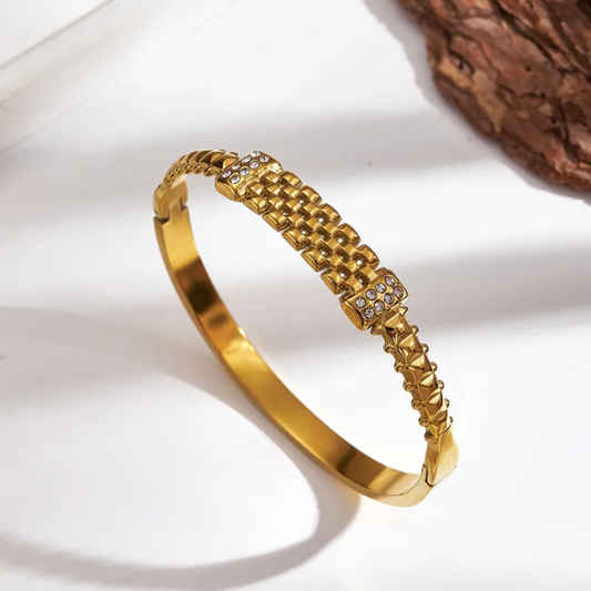 Gold bracelet with textured design on a white background