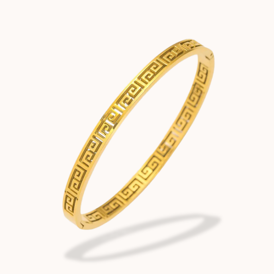 Gold bracelet with a Greek key pattern on a white background
