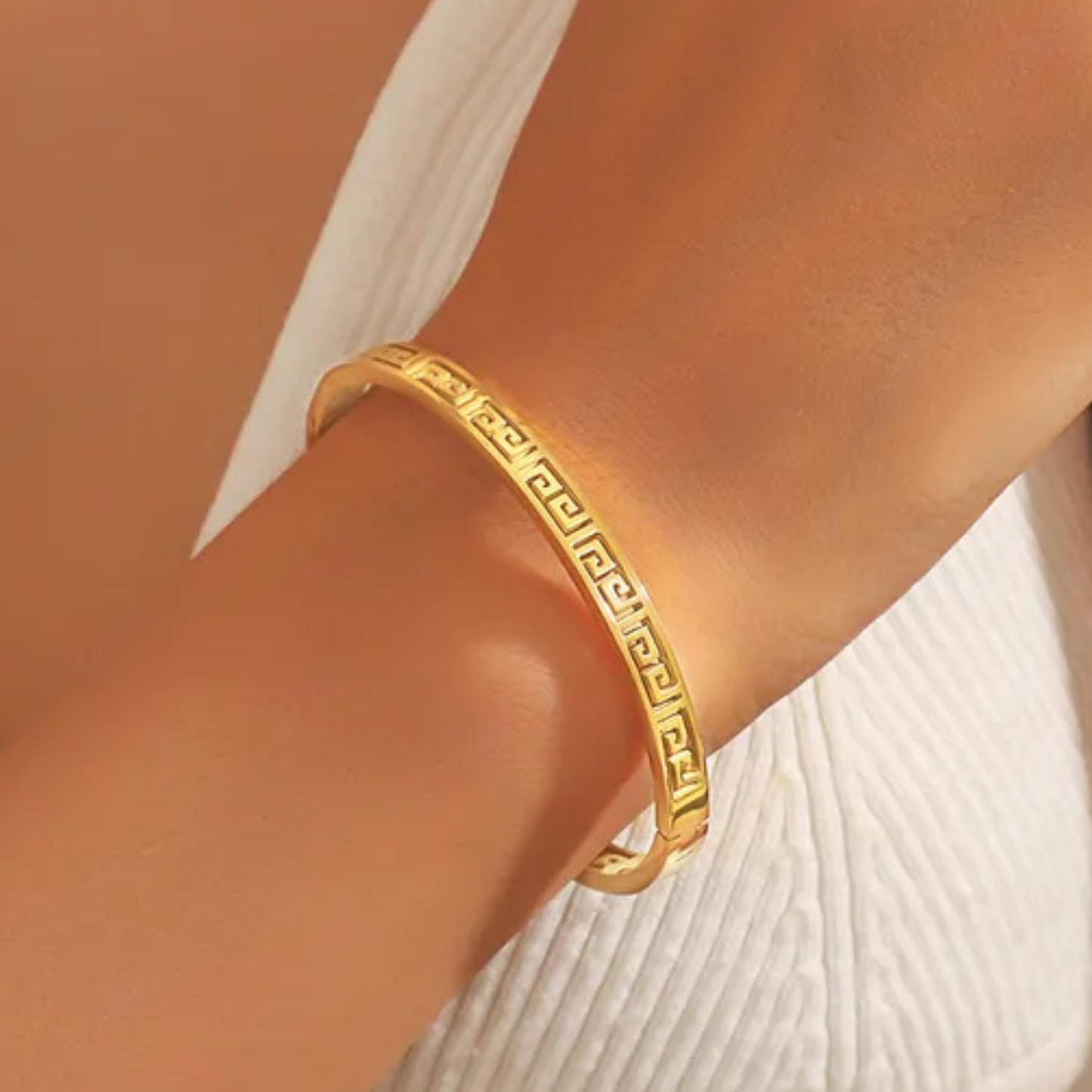 Gold bracelet on a person's wrist with a neutral background
