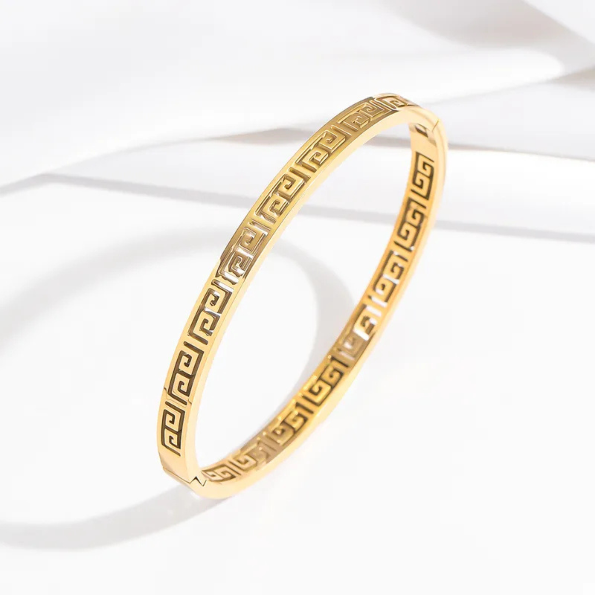 Gold bracelet with intricate design on a white background