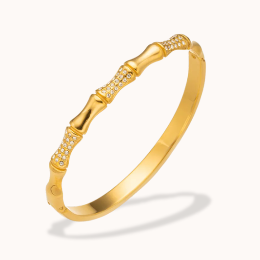Gold bracelet with bamboo design on a white background