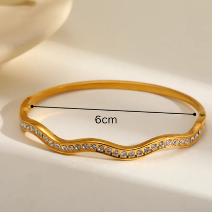 Gold bracelet with diamond accents and measurement label on a beige background