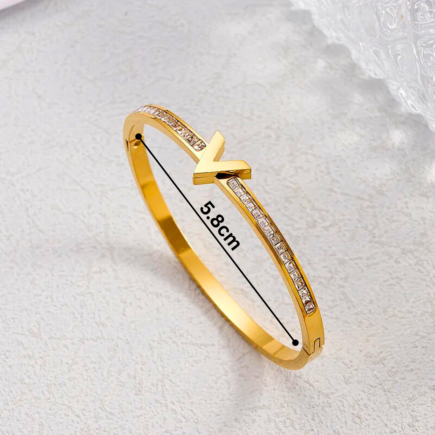 Gold bracelet with measurement on a textured white background
