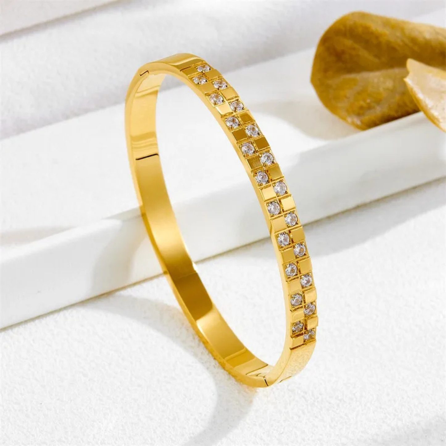 Gold bracelet with embedded diamonds on a white surface
