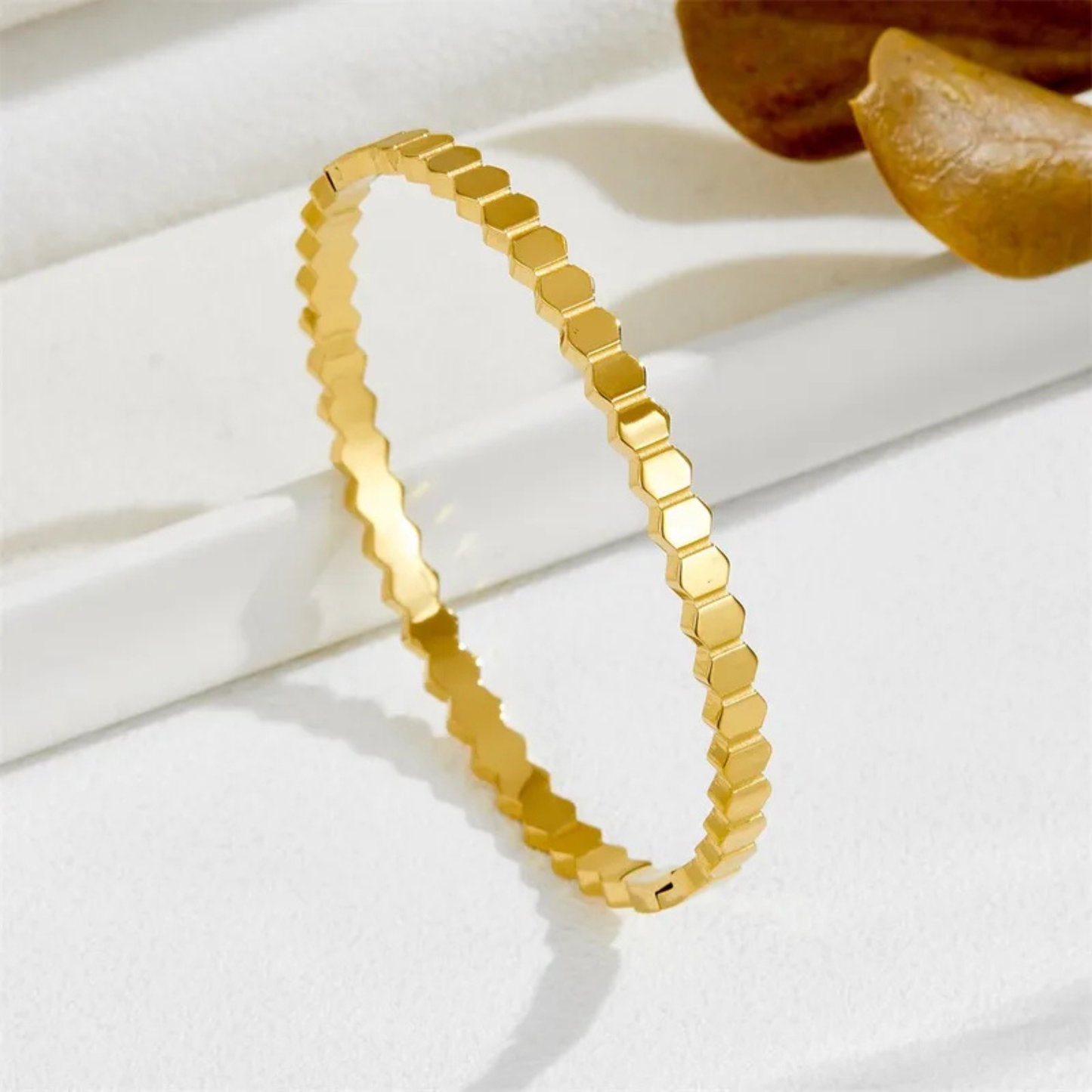 Gold bracelet with hexagonal pattern on a white surface