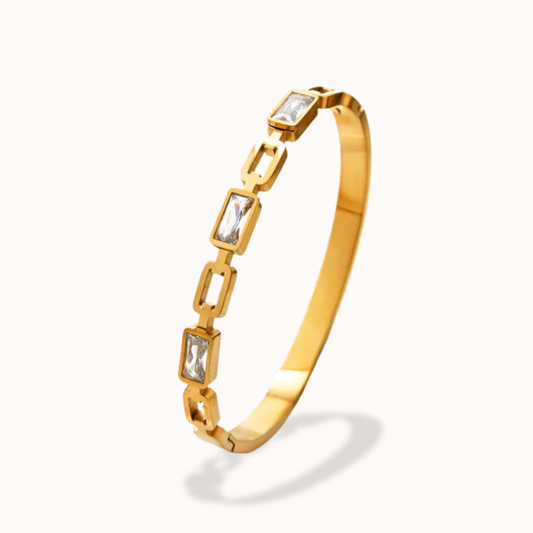 Gold bracelet with square gemstones on a white background