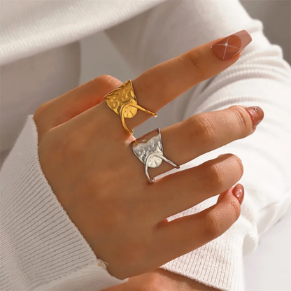 Hand wearing two ginkgo leaf rings with a neutral background