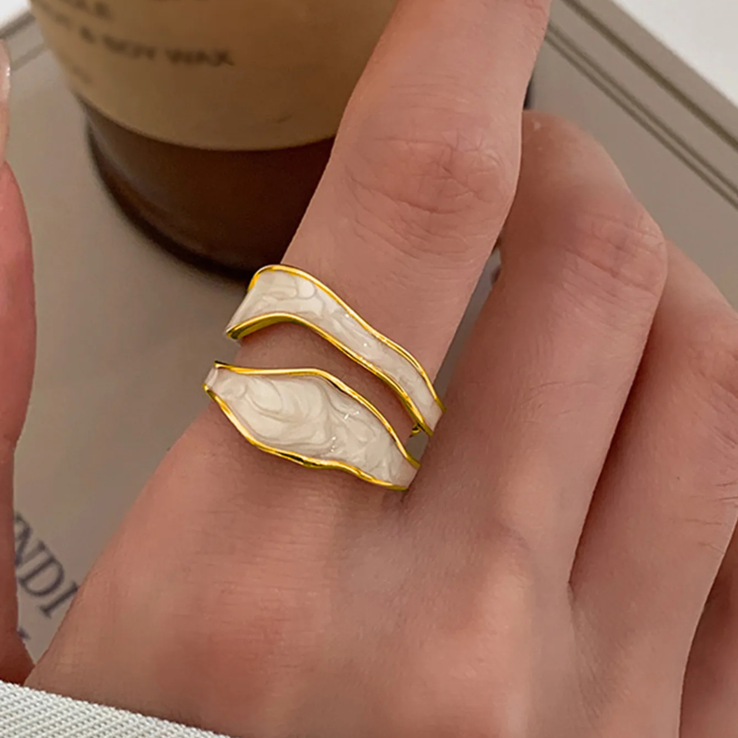 Hand wearing a white and gold ring with a blurred background