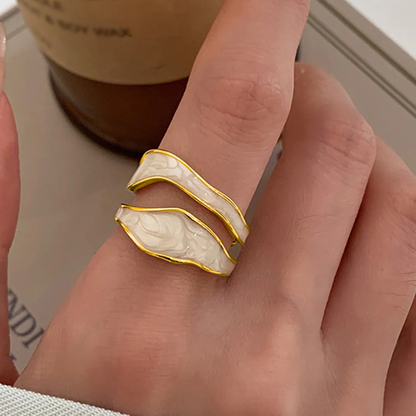Hand wearing a white and gold ring with a blurred background