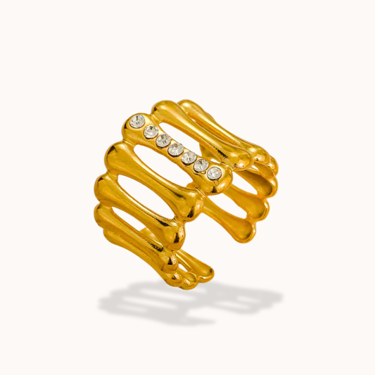 Gold skeleton hand ring with embedded crystals on a white background
