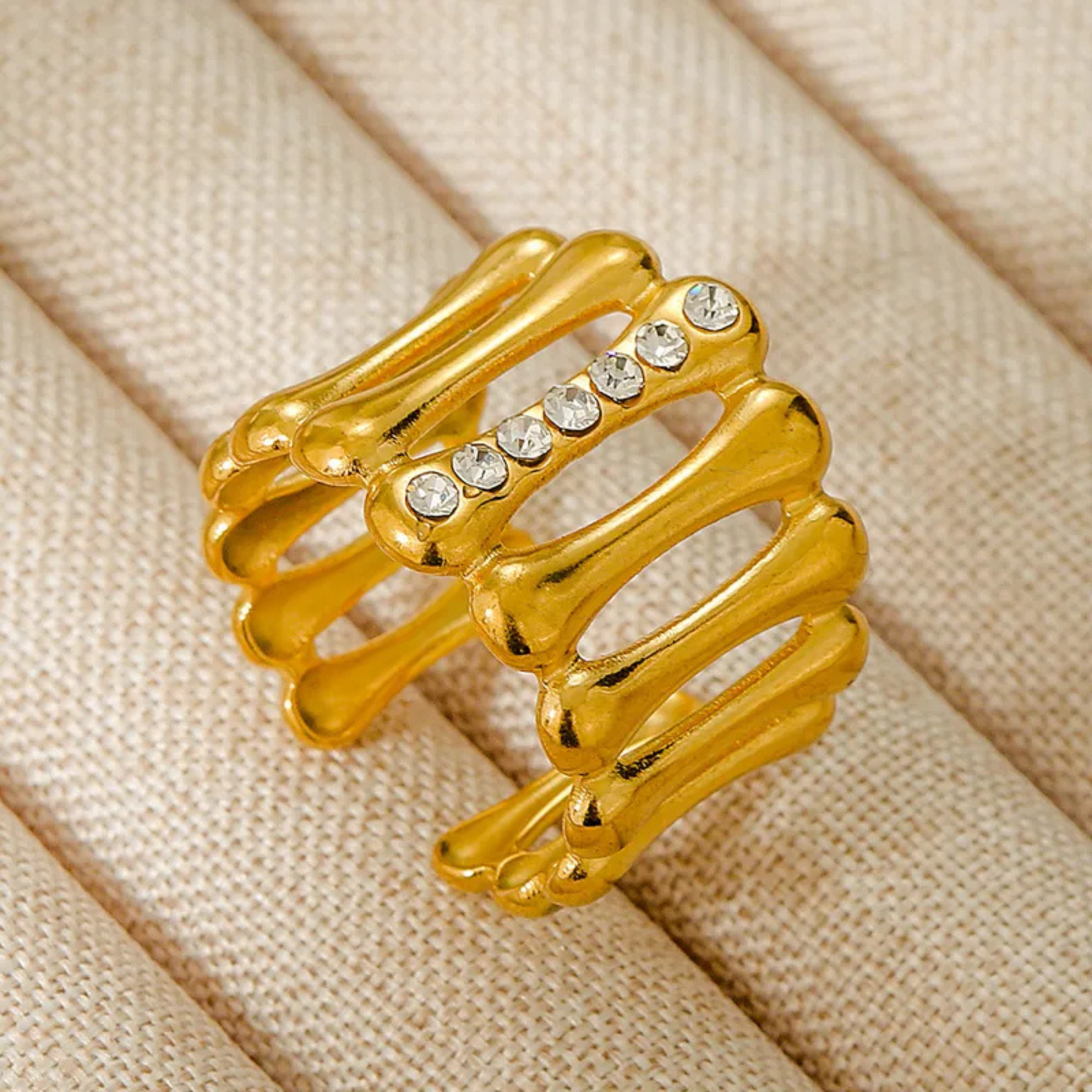 Gold ring with crystal stones on a beige fabric background