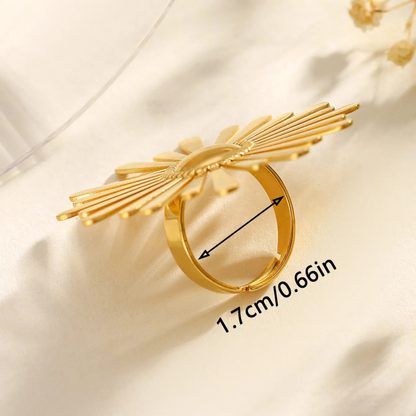 Gold ring with leaf-like design on a beige background