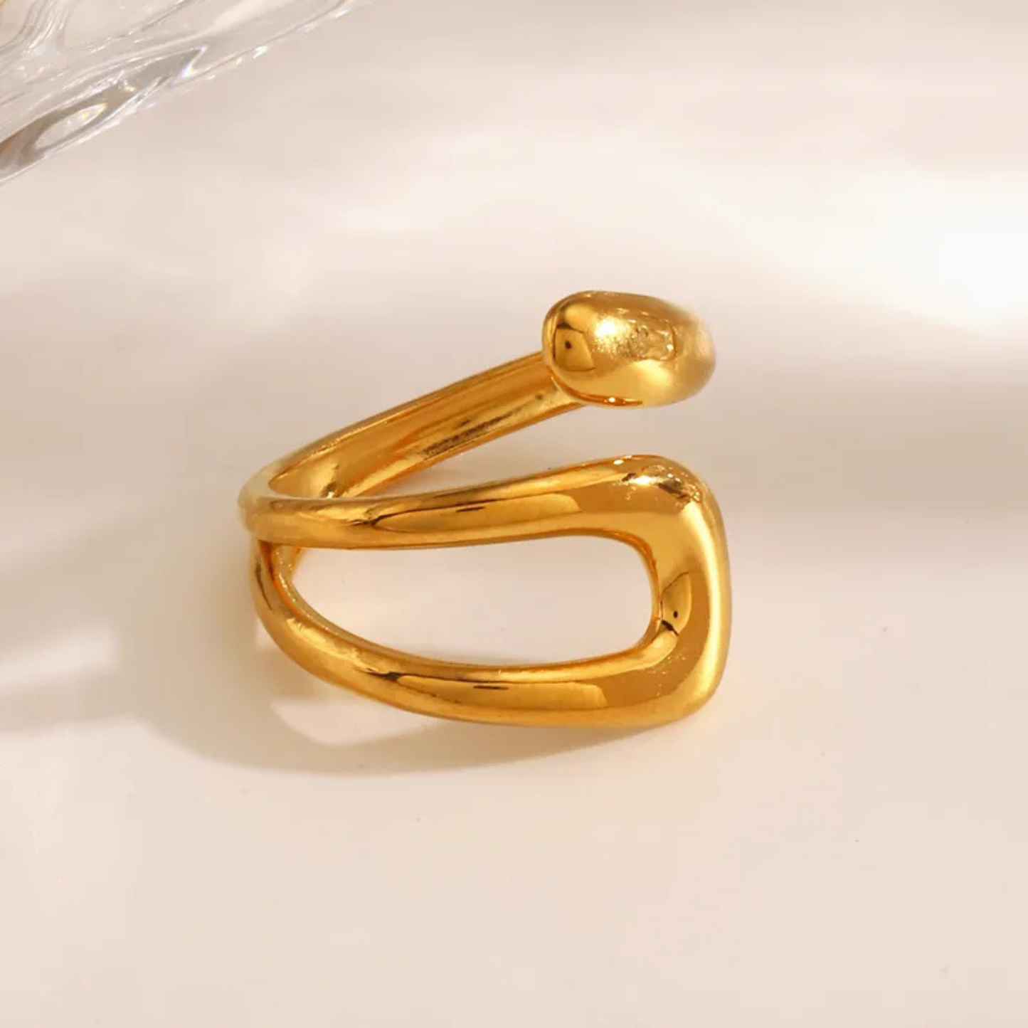 Gold snake-shaped ring on a light beige background