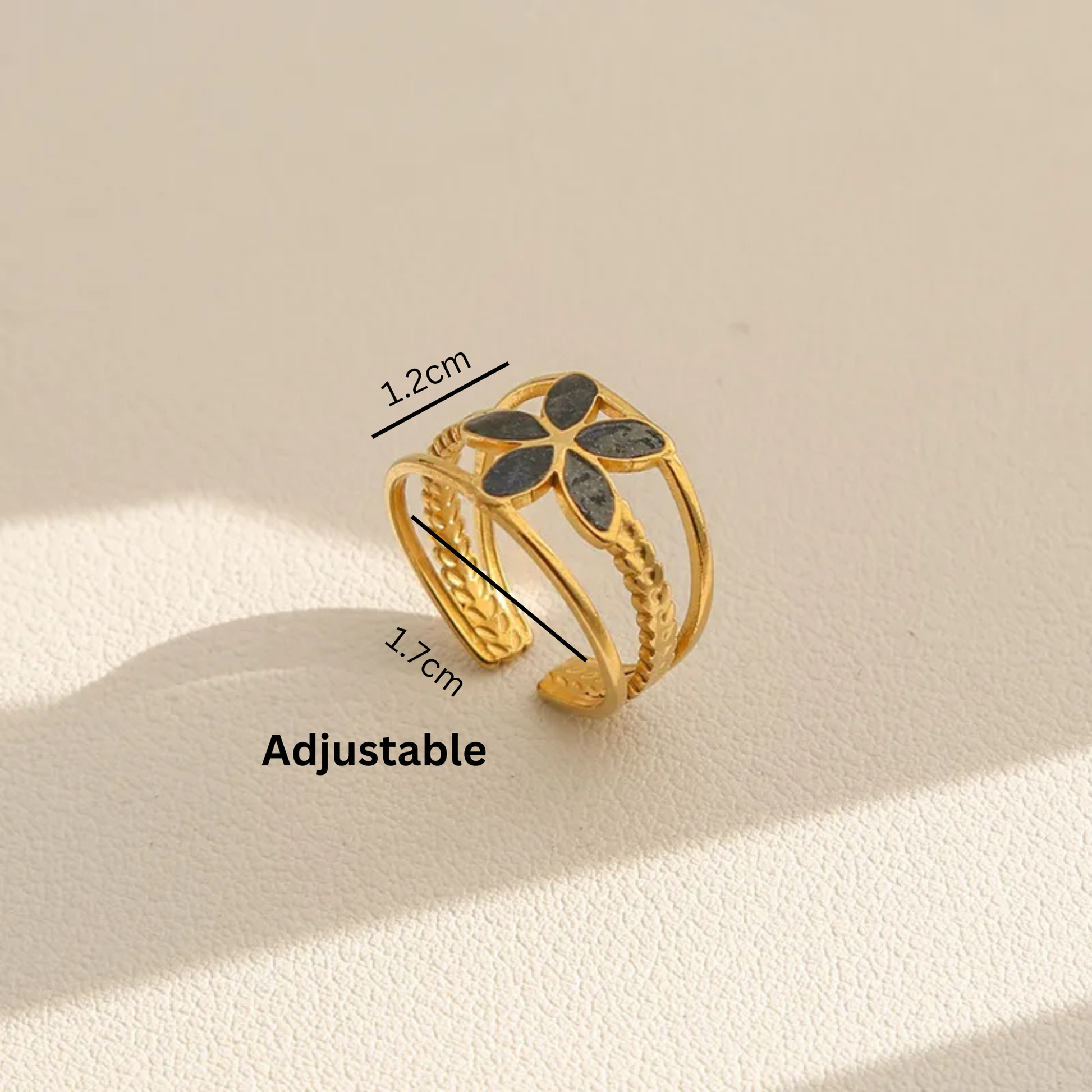 Gold adjustable ring with black stones on a beige background