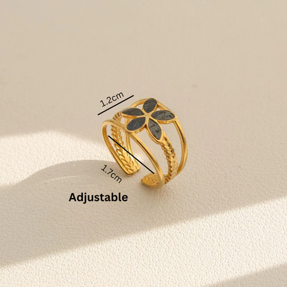 Gold adjustable ring with black stones on a beige background