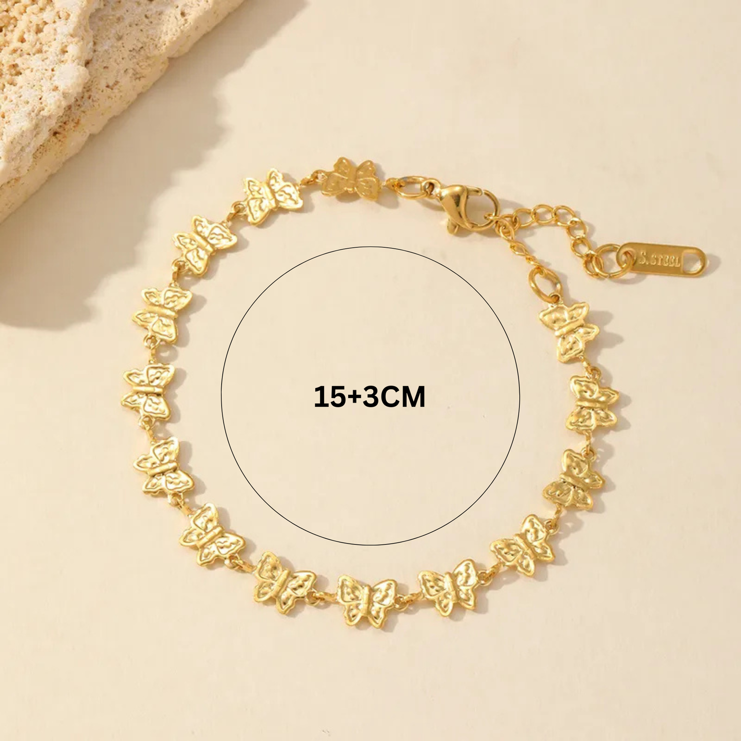 Gold bracelet with butterfly designs on a beige background