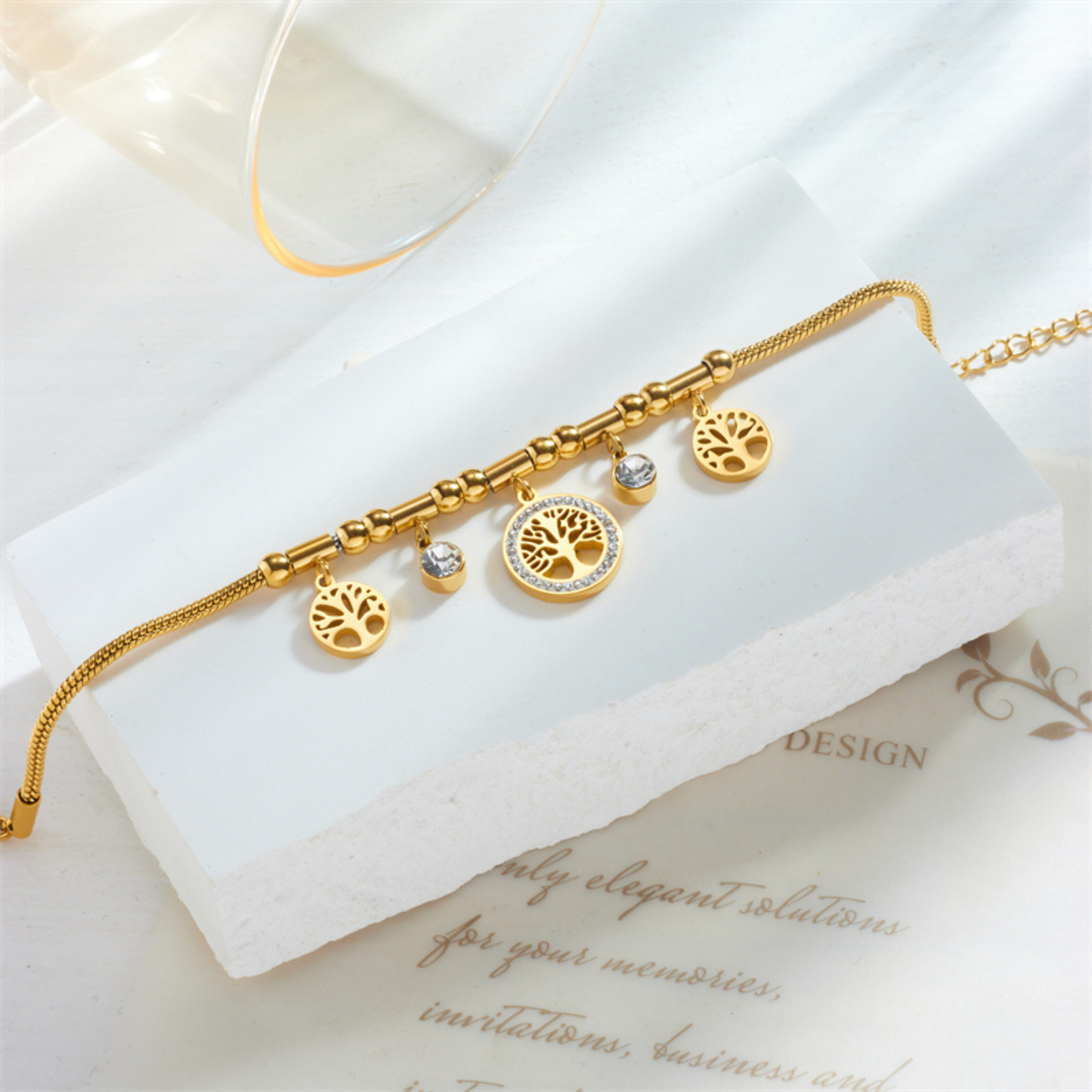 Gold bracelet with tree of life charms on a white surface