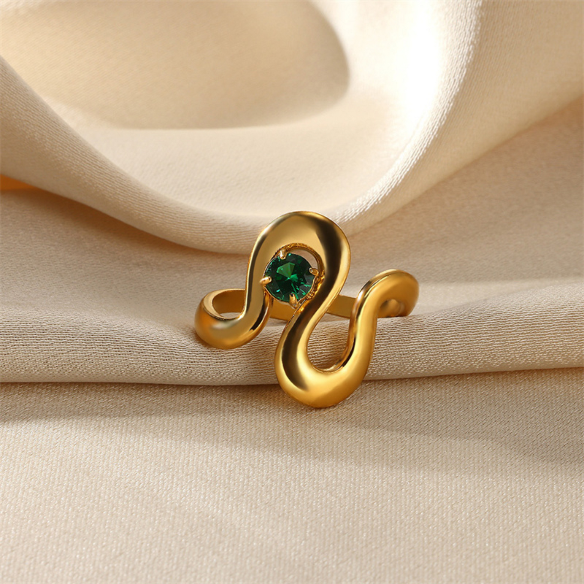 Gold ring with a green gemstone on beige fabric