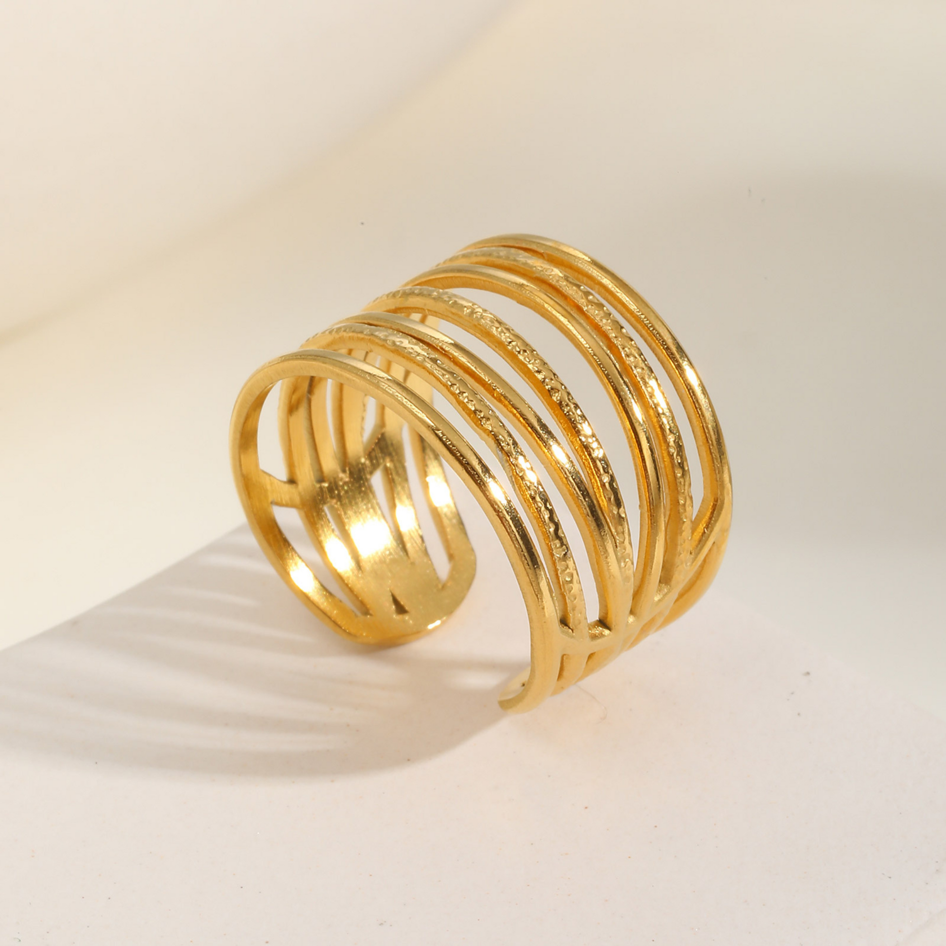 Gold ring with multiple loops on a beige background