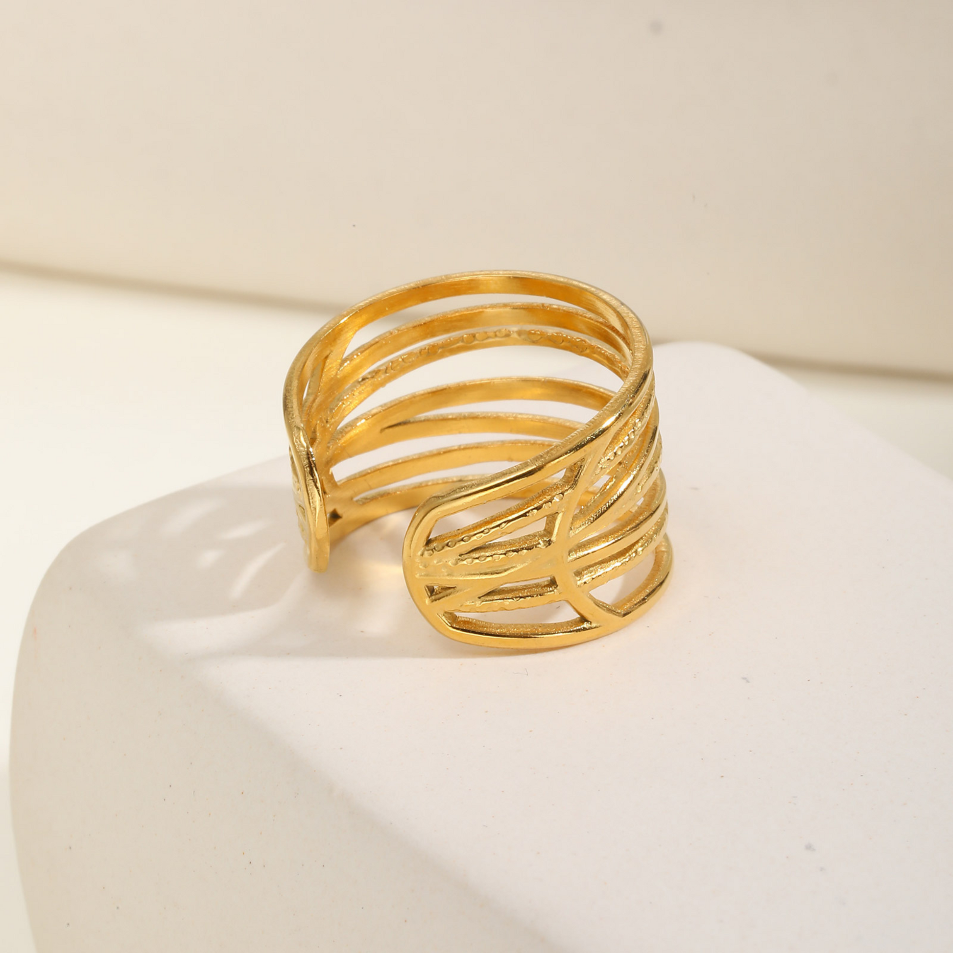 Gold ring on a white surface with a beige background