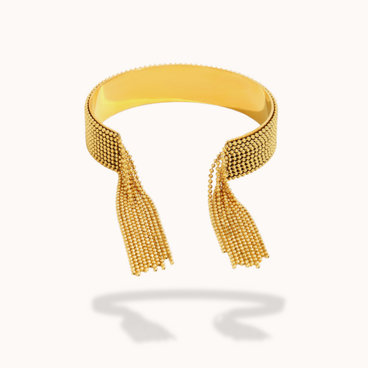 Gold bracelet with tassels on a white background