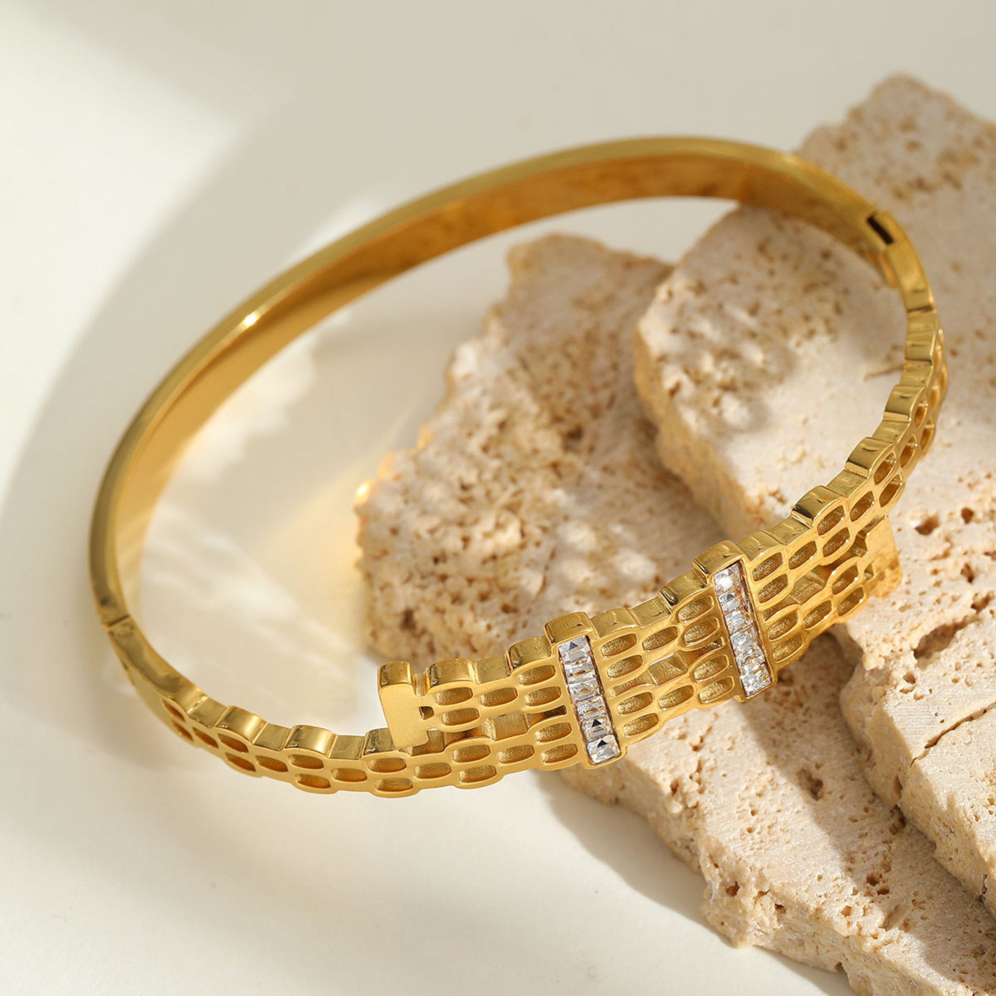 Gold bracelet with diamond accents on a textured beige surface