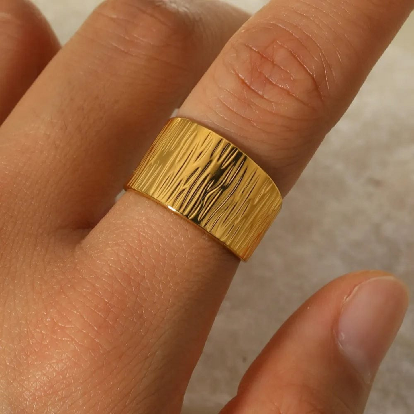 Gold ring on a finger with a neutral background