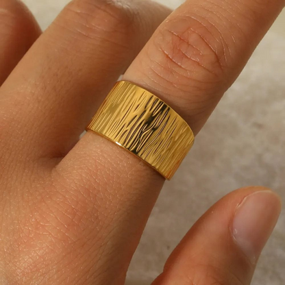 Gold ring on a finger with a neutral background