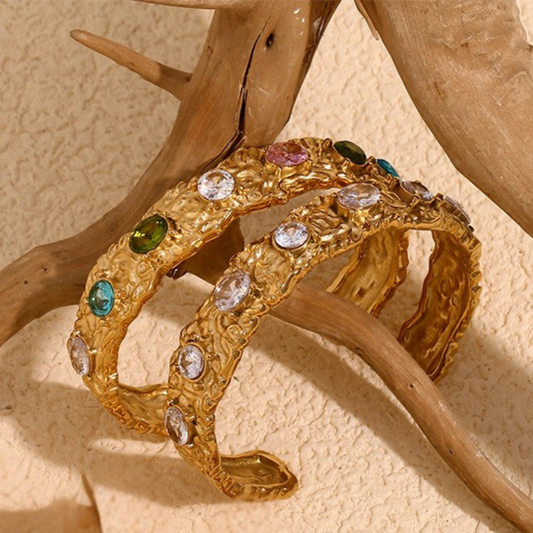 Gold bracelet with gemstones on a wooden surface
