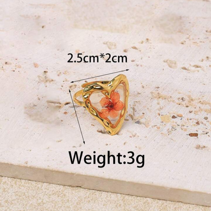 Gold ring with a floral design on a textured surface, showing measurements and weight.