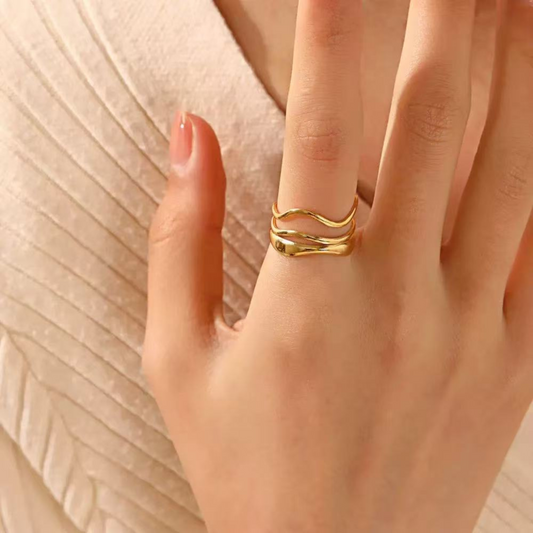Gold ring on a person's finger with a soft beige background