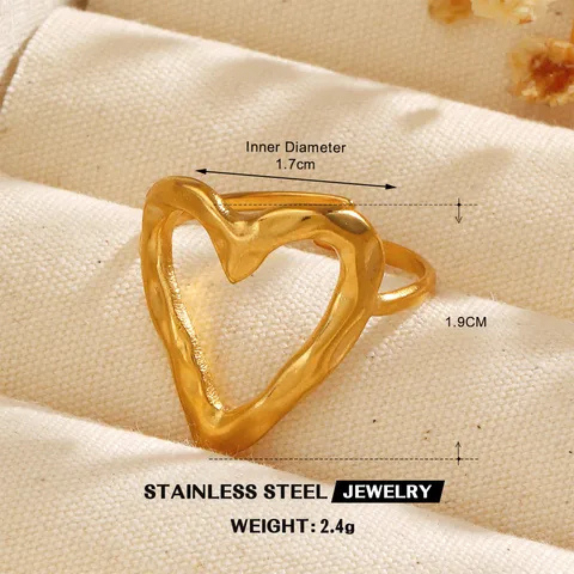 Gold heart-shaped ring with measurements on a beige fabric background