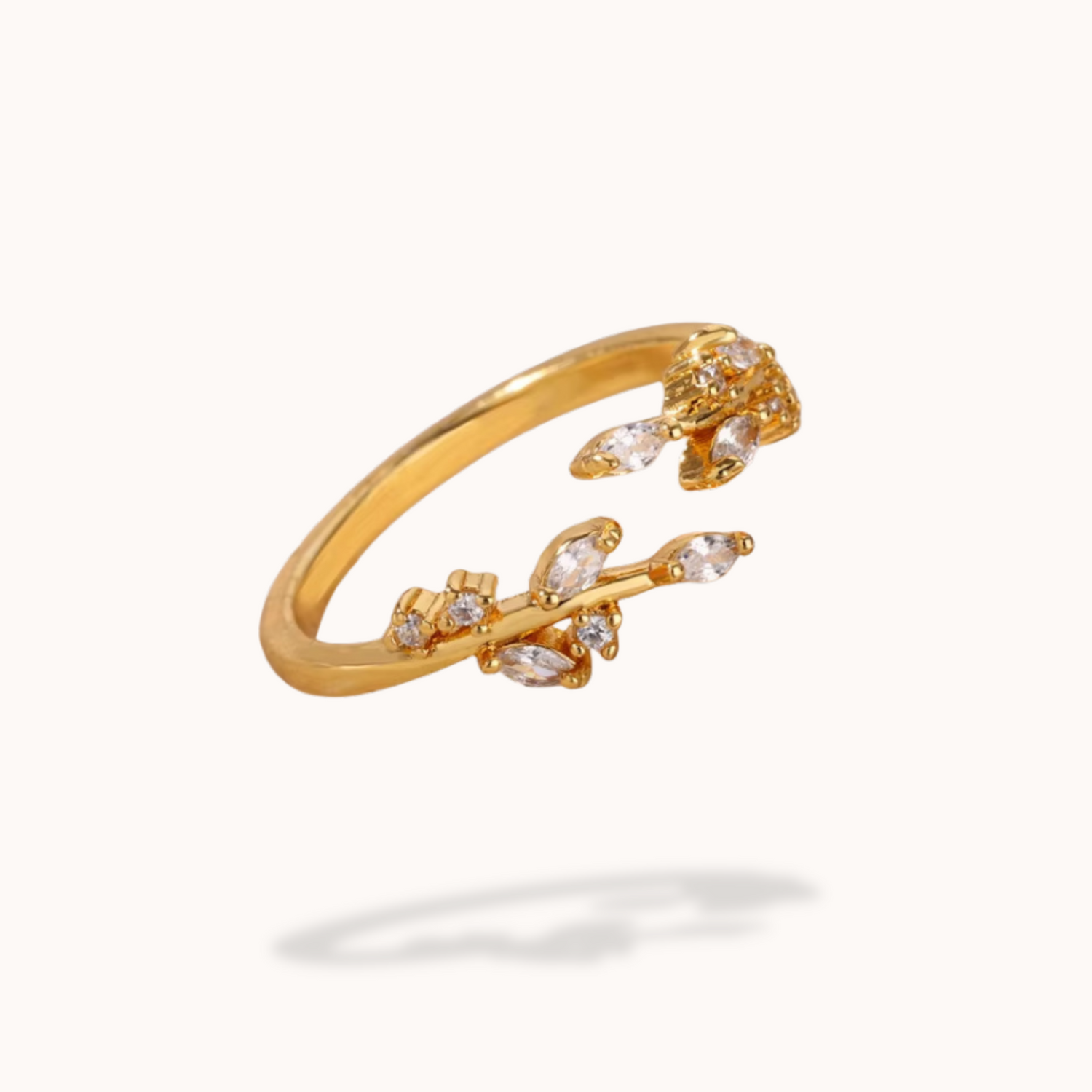 Gold open ring with floral designs and small stones on a white background