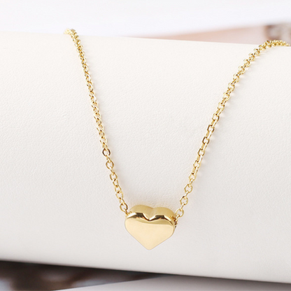 Gold heart-shaped necklace on a white surface